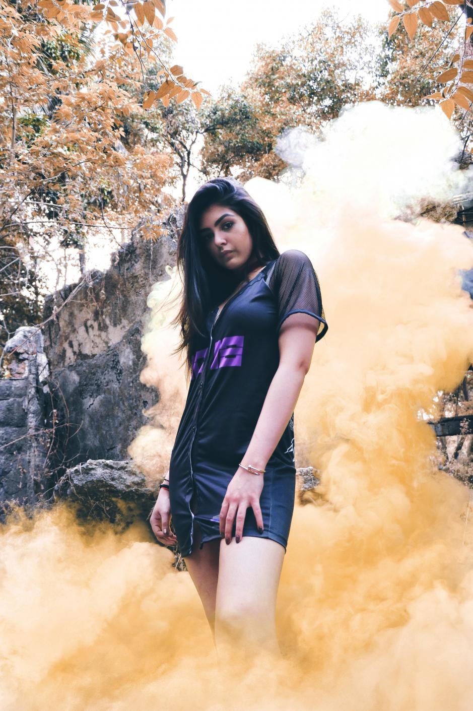 A girl Wearing 3018 Black polyester short sleeve jersey dress is standing in front of yellow colored smoke.