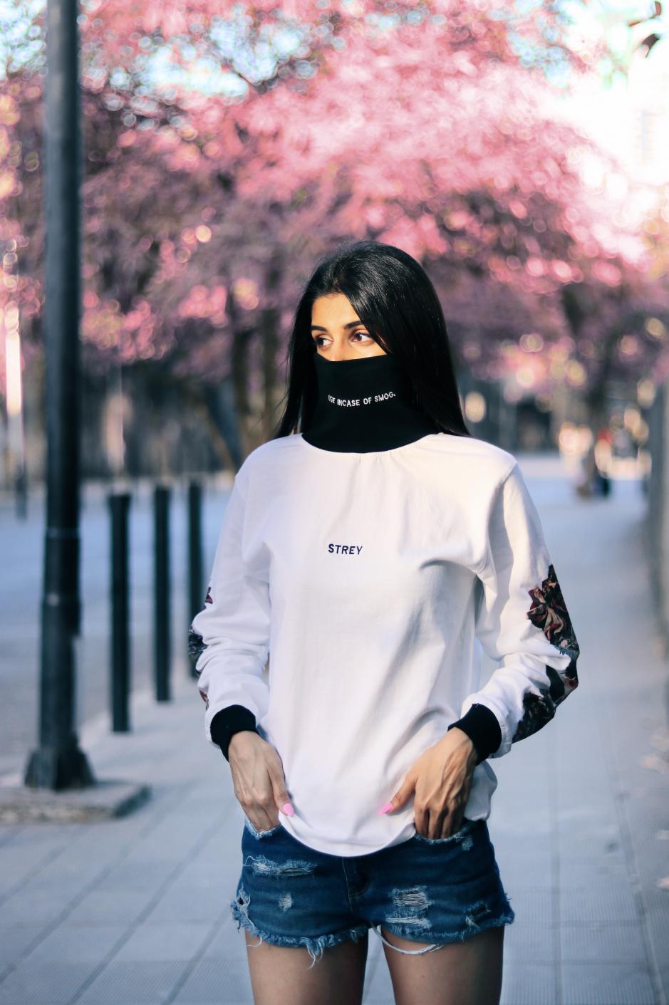 A girl wearing high neck white and black full sleeves regular fit T-shirt with flowers printed on the sleeves paired with shorts. 